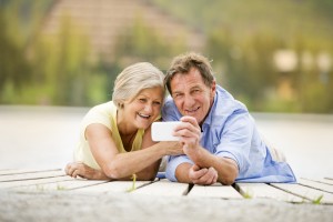 Senior couple lying down and taking selfie on pier